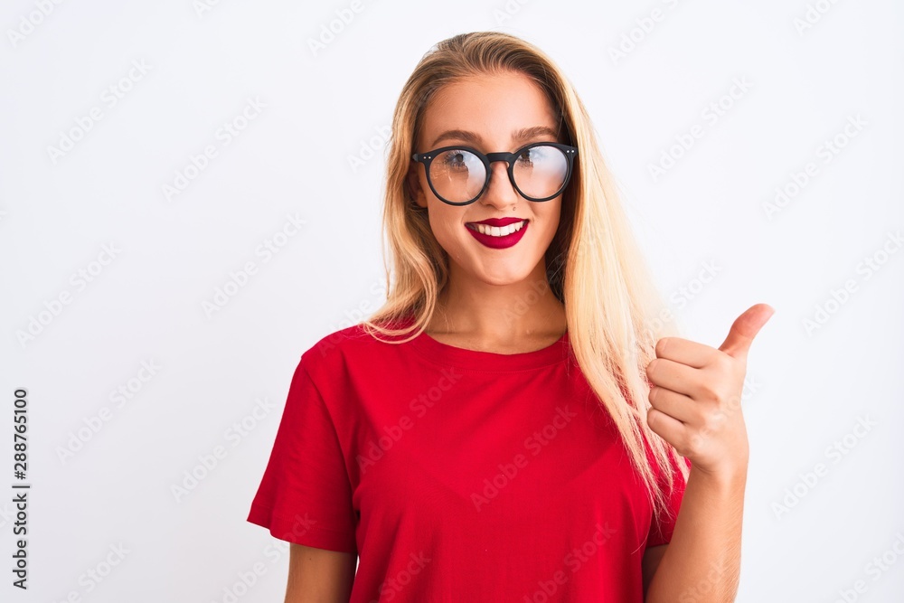 Young beautiful woman wearing red t-shirt and glasses standing over isolated white background doing happy thumbs up gesture with hand. Approving expression looking at the camera with showing success.