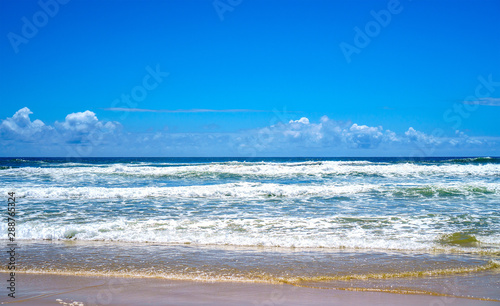 Stunning panoramic view of the ocean and beautiful waves rolling in on a sandy beach.
