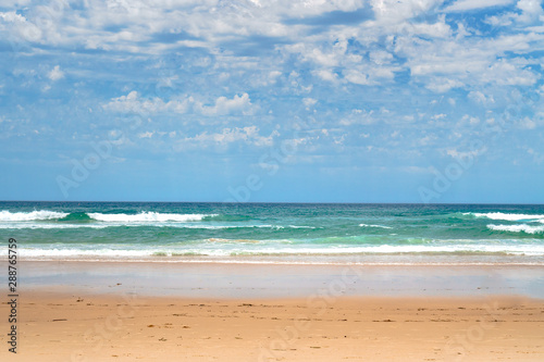 Stunning panoramic view of the ocean and beautiful waves rolling in on a sandy beach.