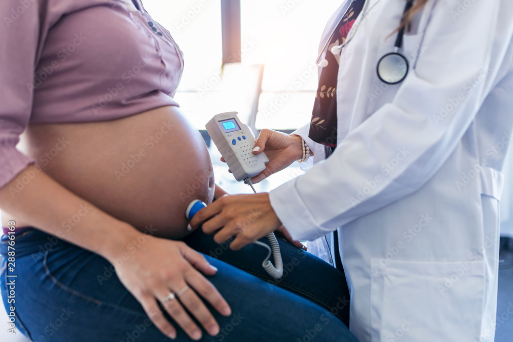 Obstetrician gynecologist performing Doppler auscultation checking ...