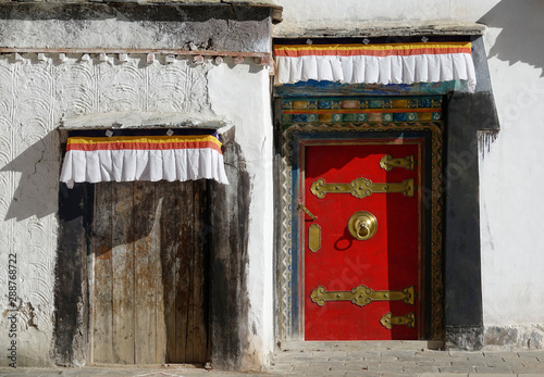 CLOSE UP: Beautiful shot of a brown wooden door next to a red and gilded door. photo