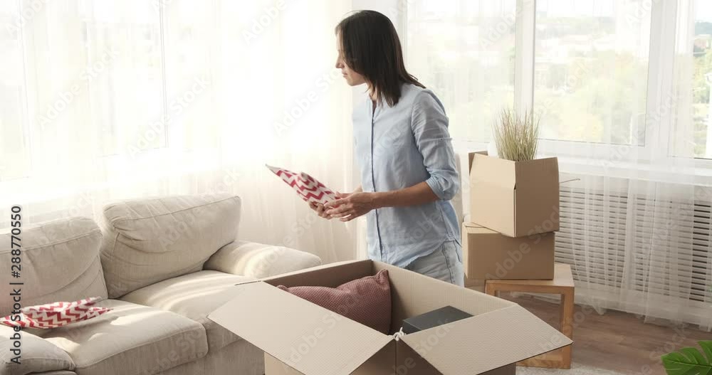 Young woman unpacking carton boxes moving into her new house Young woman unpacking carton boxes moving into her new house