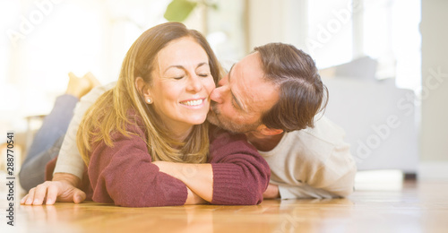 Beautiful romantic couple sitting together on the floor kissing in love at home