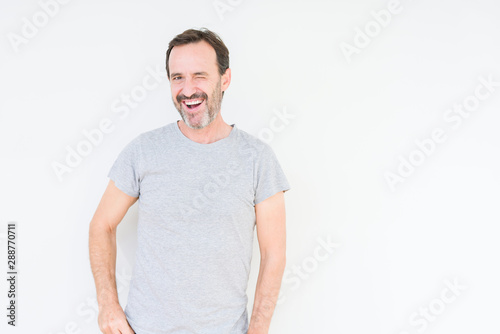 Handsome senior man over isolated background winking looking at the camera with sexy expression, cheerful and happy face. © Krakenimages.com