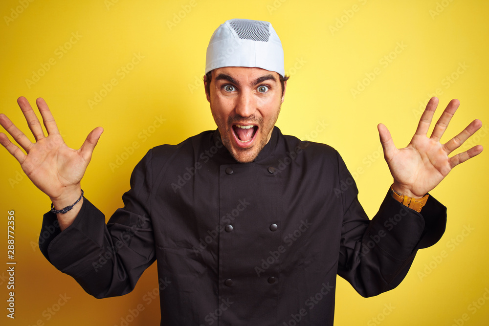 Young handsome chef man cooking wearing uniform and hat over isolated yellow background celebrating crazy and amazed for success with arms raised and open eyes screaming excited. Winner concept