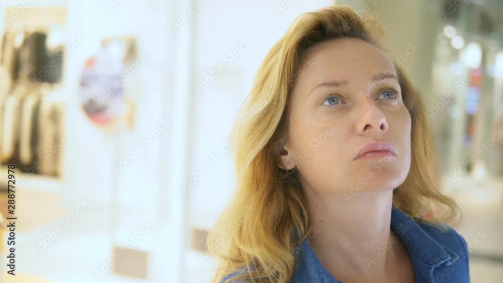 woman is looking at shop windows in a large supermarket. face close up woman is looking at shop windows in a large supermarket. face close up