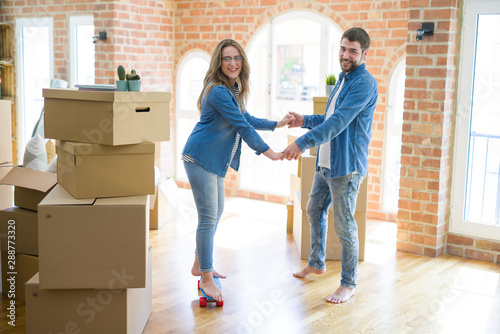 Young couple moving to a new home, having fun riding a skateboard at new apartment around cardboard boxes © Krakenimages.com