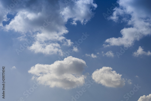 The clouds. The light of the sun through the clouds against a bright sky at sunset. Clouds on the blue sky. Sunset.