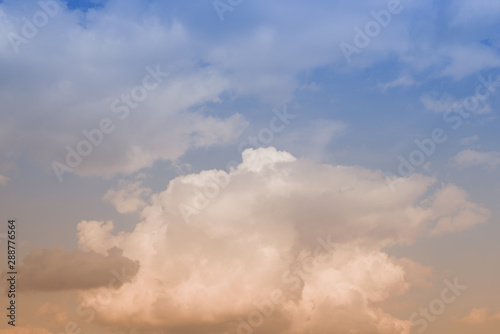 The clouds. The light of the sun through the clouds against a bright sky at sunset. Clouds on the blue sky. Sunset.