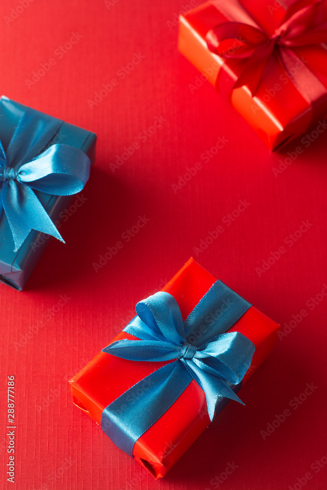 Blue and red gift boxes with red ribbon and bow isolated on red background, top view. Christms, party concept. Blue and red gift boxes with red ribbon and bow isolated on red background, top view. Christms, party concept.
