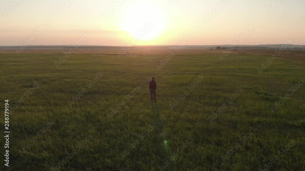 Silhouette young farmer going on the field at sunset with wooden box with fresh vegetables. Healthy eating, autumn harvest, farming concept. Silhouette young farmer going on the field at sunset with wooden box with fresh vegetables. Healthy eating, autumn harvest, farming concept.