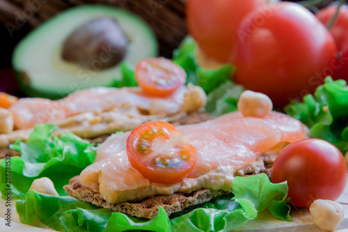 Crispbread with hummus and salmon on vegetable background