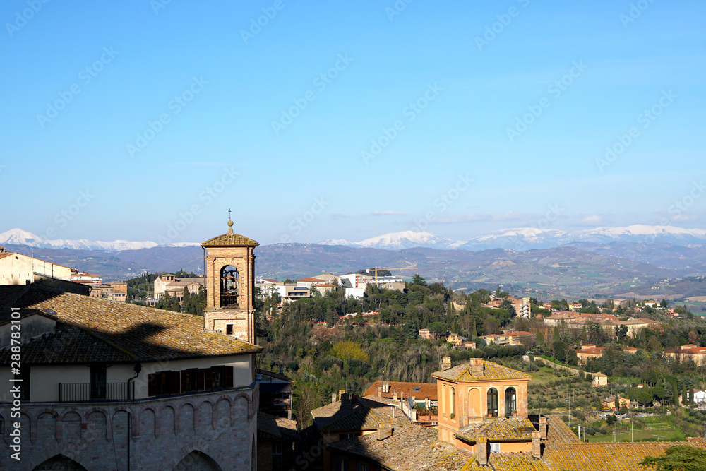 Skyline of Assisi in Umbria with snow covered mountains in the background                               