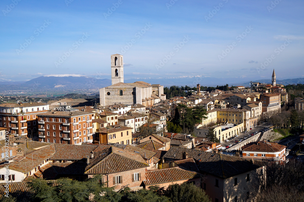 Skyline of Assisi in Umbria with snow covered mountains in the background                               