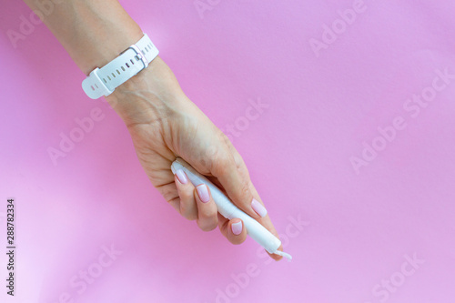 Close-up of beautiful female hand with perfect nude soft pink manicure holding clean cotton tampon for women period. Feminine hygiene products