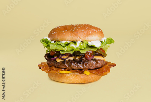 Bacon cheeseburger with onion, mustard, pickles, lettuce, ketchup and mayonnaise on a sesame bun photo