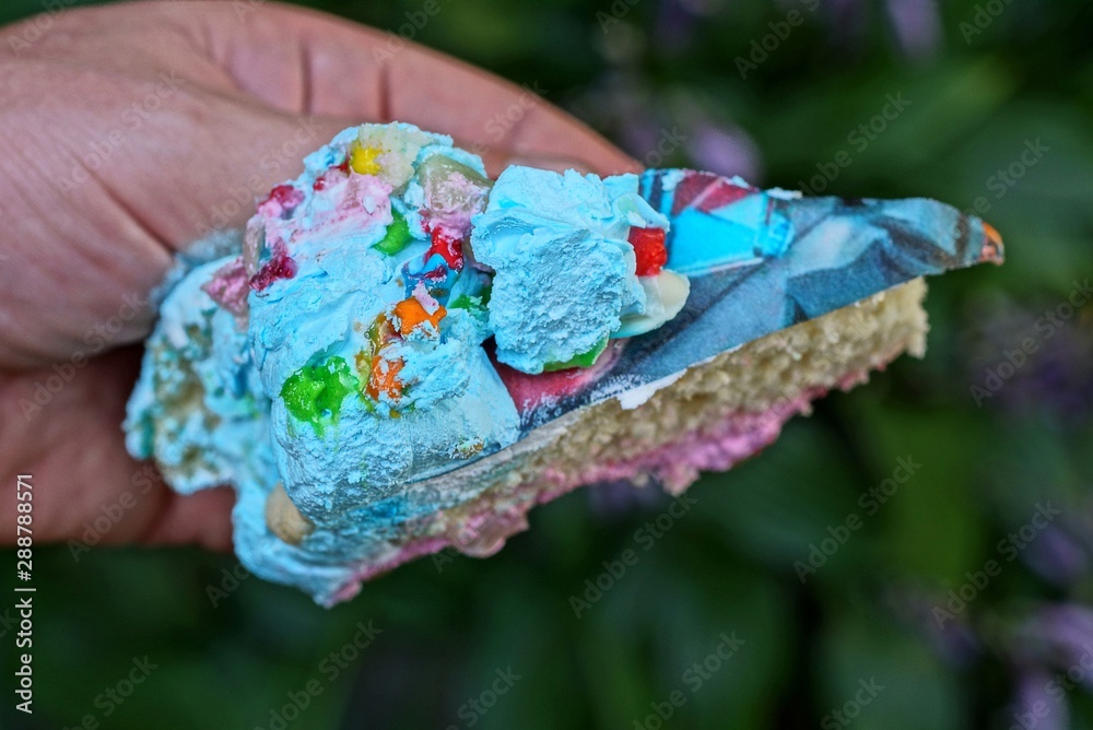 one large colored piece of cake lies on the fingers
