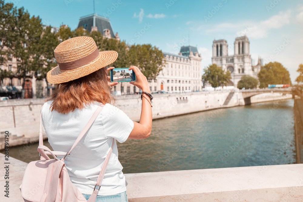 Happy traveler girl blogger takes photos of Notre Dame De Paris