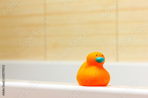Rubber orange Duck in bathtub on beige background. Space for text