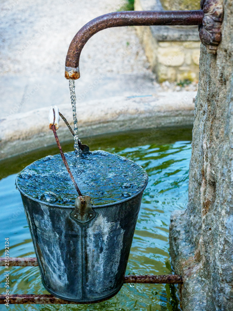 Water overflowing pail in fountain Stock Photo