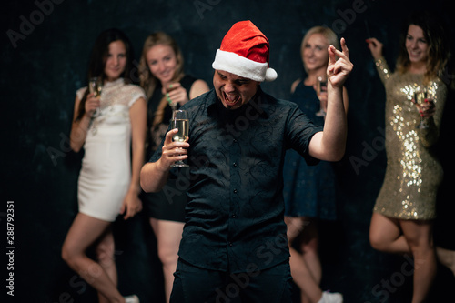 New Year party in night club, Christmas celebration atmosphere. Joyful man on dance floor drinking champagne, modern youth life