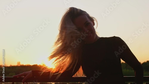 Happy Portrait Of Beautiful Adult Woman In Her 30s laughing out loud and shake her head Backlit At Sunset In Slomo photo