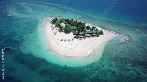 Southsea idyllic paradise island aerial view, Fiji. Ascending above turquoise blue coral reef ocean tiny tourist retreat. photo