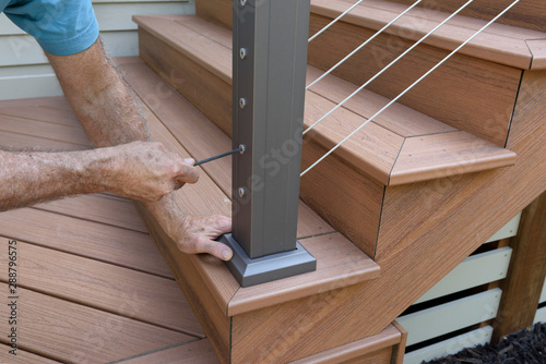 Worker Installing Wire Railing on New Deck