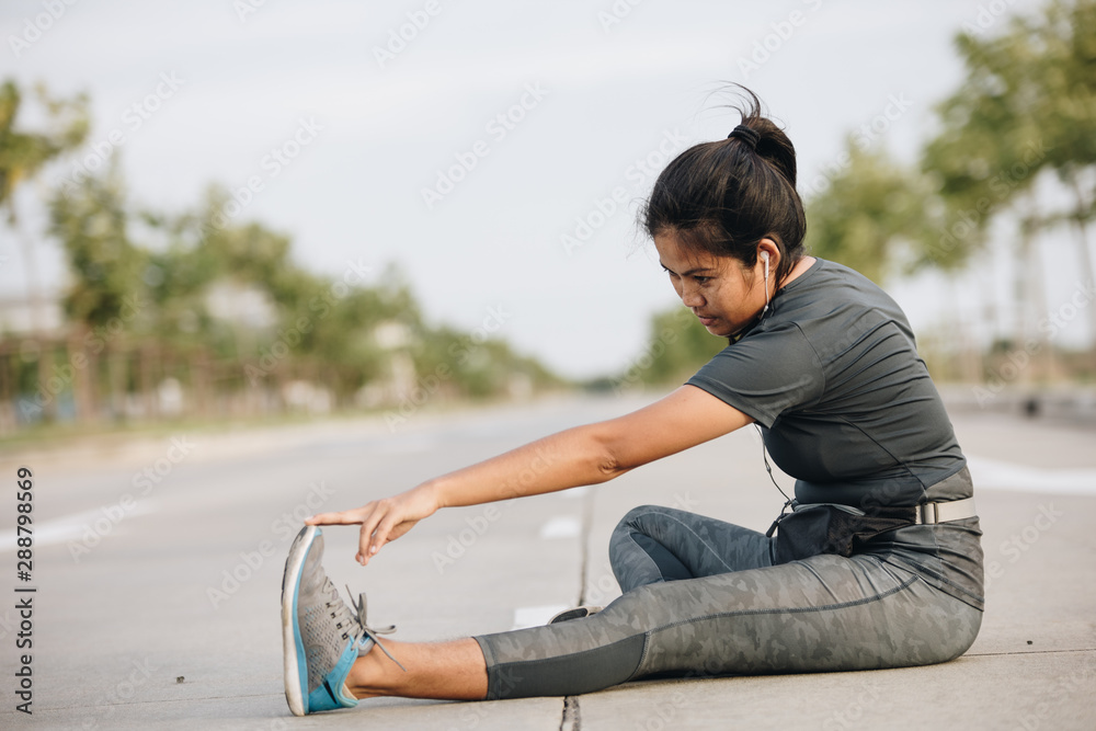 Sports young woman stretching before running outdoors