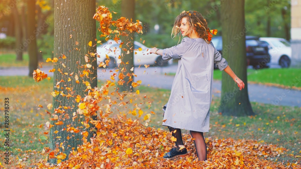 Cute young hipster millennial girl in purple blue autumn dress throwing dry  fall leaves up in air kicking. Happy woman atmospheric autumn relax Freedom  mind peace wind fresh breath concept banner. Stock