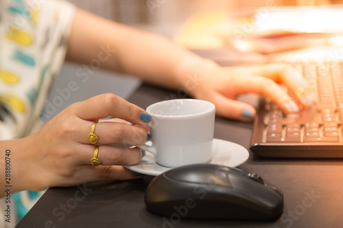 Woman hand holdding coffee cup with working table