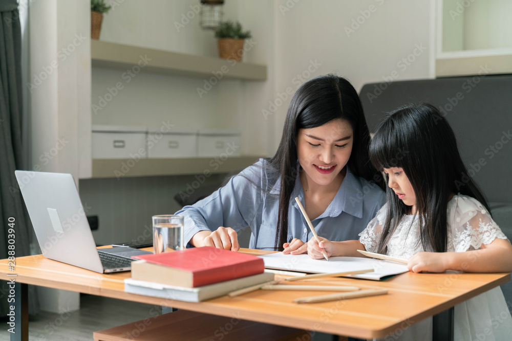 Beautiful business mom is using a laptop teaching homework with kids at home Beautiful business mom is using a laptop teaching homework with kids at home