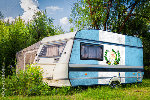 A car trailer, a motor home, painted in the national flag of  Guatemala stands parked in a mountainous. The concept of road transport, trade, export and import between countries.