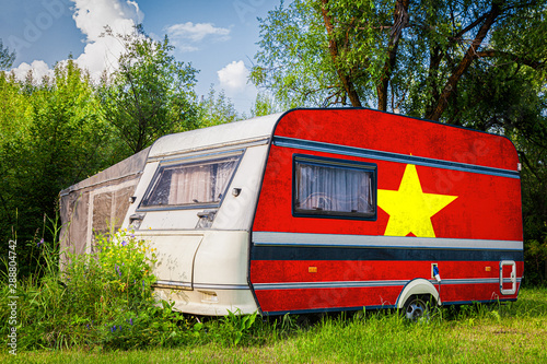 A car trailer, a motor home, painted in the national flag of  Vietnam stands parked in a mountainous. The concept of road transport, trade, export and import between countries.