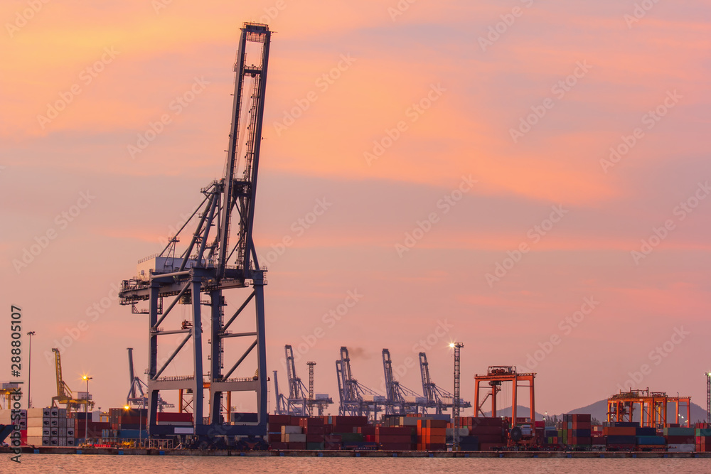 Cargo cranes in industrial port at sunset.
