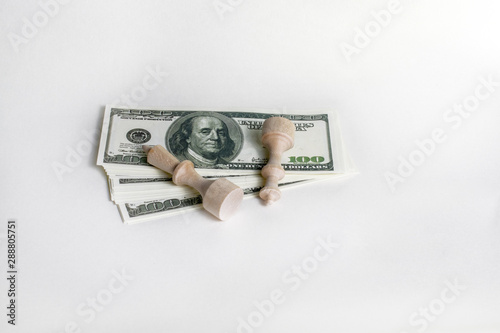 white chess pieces fell on banknotes of money on a light background