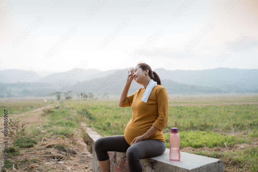 Fototapeta premium pregnant woman sit while jogging outdoor take a break