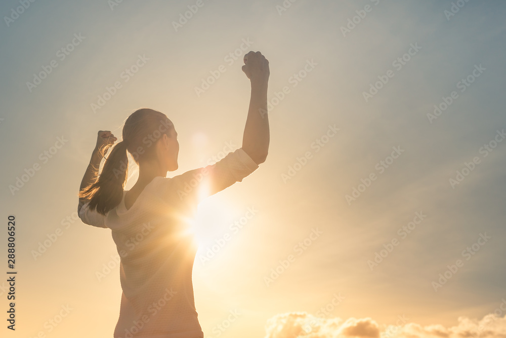 Strong confident woman flexing arms facing the sunset.  - obrazy, fototapety, plakaty 