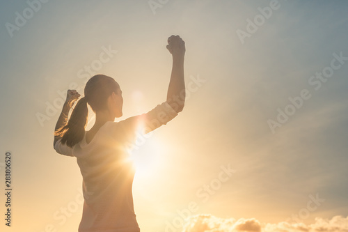 Strong confident woman flexing arms facing the sunset.  photo