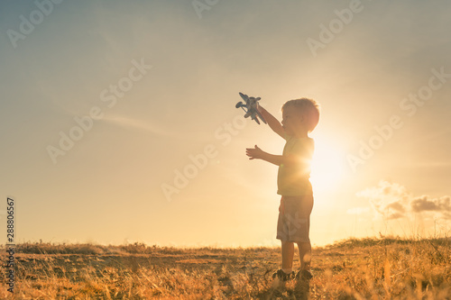 Little boy playing outdoors holding up top airplane in the sky.  © kieferpix