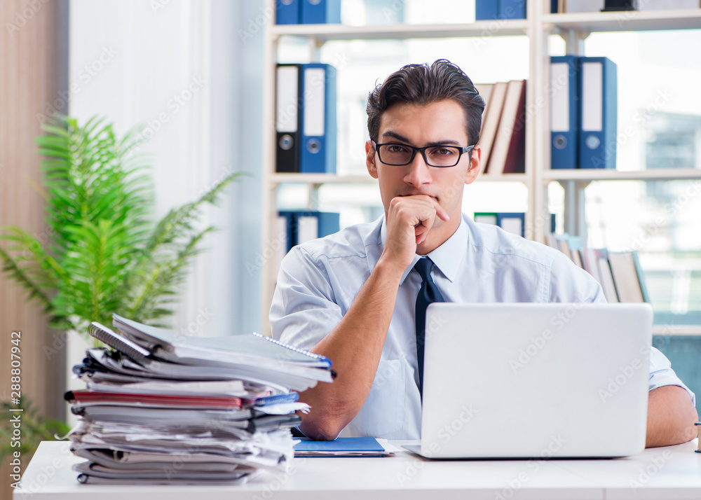 Businessman with excessive work paperwork working in office Businessman with excessive work paperwork working in office