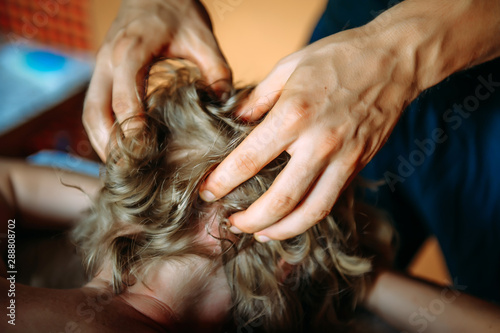 Woman gets professional head massage, close-up. Men's hands doing massage of the scalp.