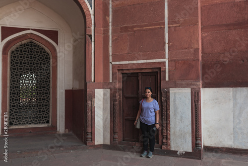 An Indian girl standing in front of an ancient red sandstone wall at Humayun's Tomb, Delhi.