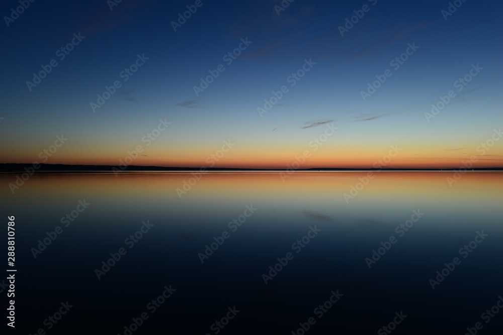 Nightfall blue hour twilight glow on the horizon in calm on the water and in the sky