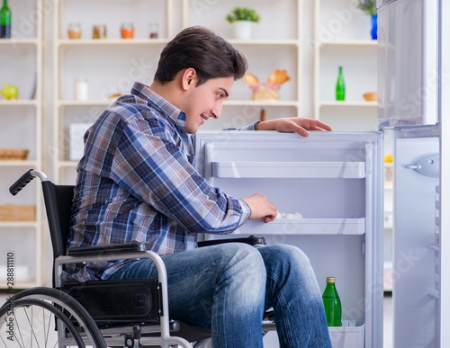 Young disabled injured man opening the fridge door © Elnur