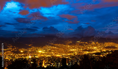 Panoramic long exposure cityscape photograph of Medellin at night with its valley illuminated in the Andes mountain range, Antioquia Department, Colombia.
