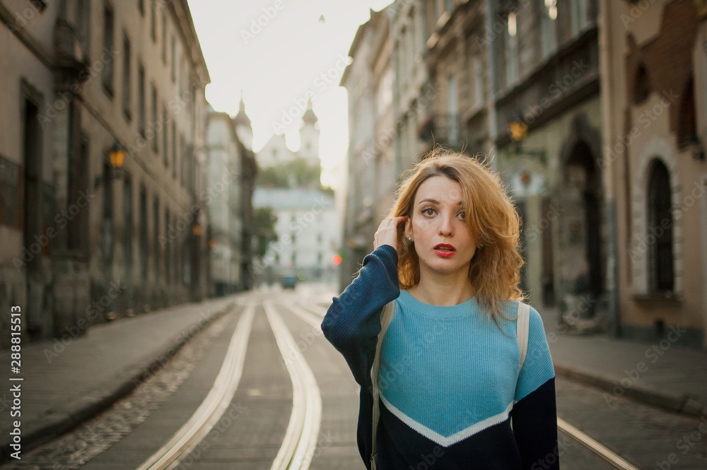 Outdoors female portrait of amazing young adult girl tourist enjoying her trip early in the morning in empty city in Europe on street with tramway background. Travelling concept