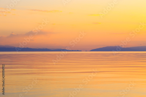 Beautiful sunset on a lake in the mountains. Kyrgyzstan  Issyk-Kul Lake. Bright sky  background in warm colors.