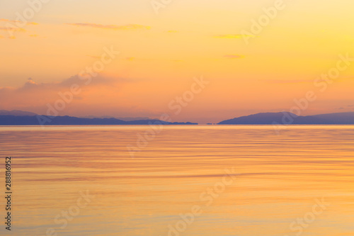 Beautiful sunset on a lake in the mountains. Kyrgyzstan, Issyk-Kul Lake. Bright sky, background in warm colors. © Alwih