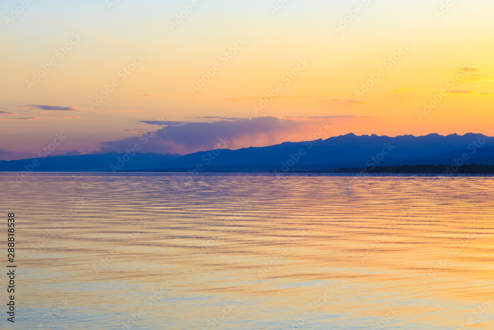 Beautiful sunset on a lake in the mountains. Kyrgyzstan, Issyk-Kul Lake. Bright sky, background in warm colors. Beautiful sunset on a lake in the mountains. Kyrgyzstan, Issyk-Kul Lake. Bright sky, background in warm colors.